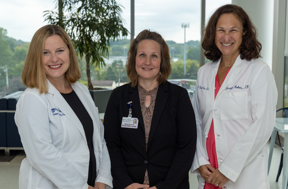 The three women who created this initiative are standing next to each other .